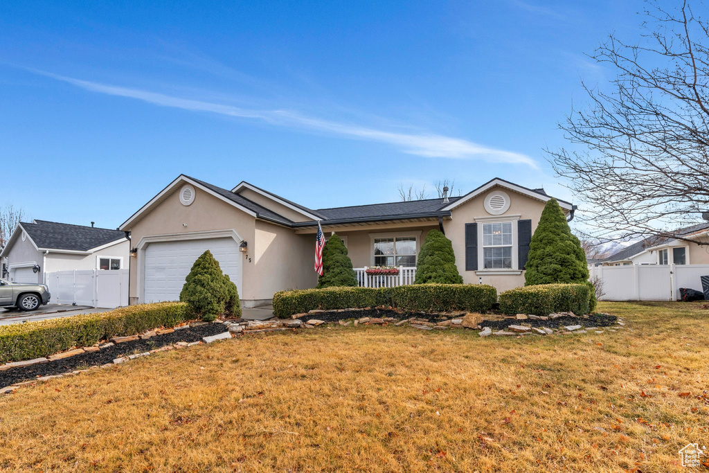 Single story home featuring a garage, fence, concrete driveway, stucco siding, and a front lawn