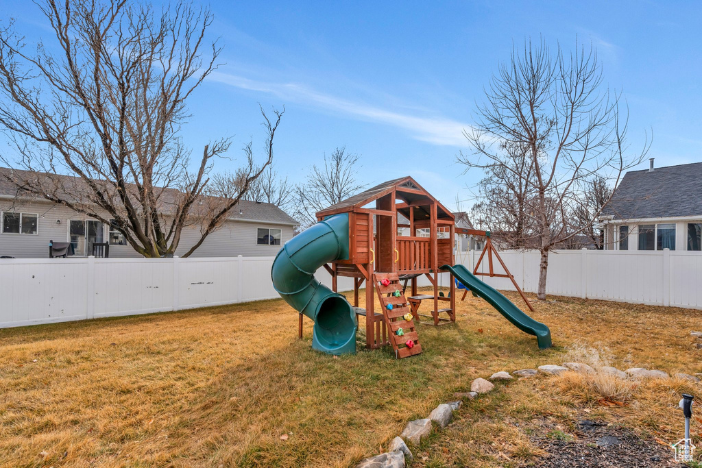 View of playground with a fenced backyard and a yard