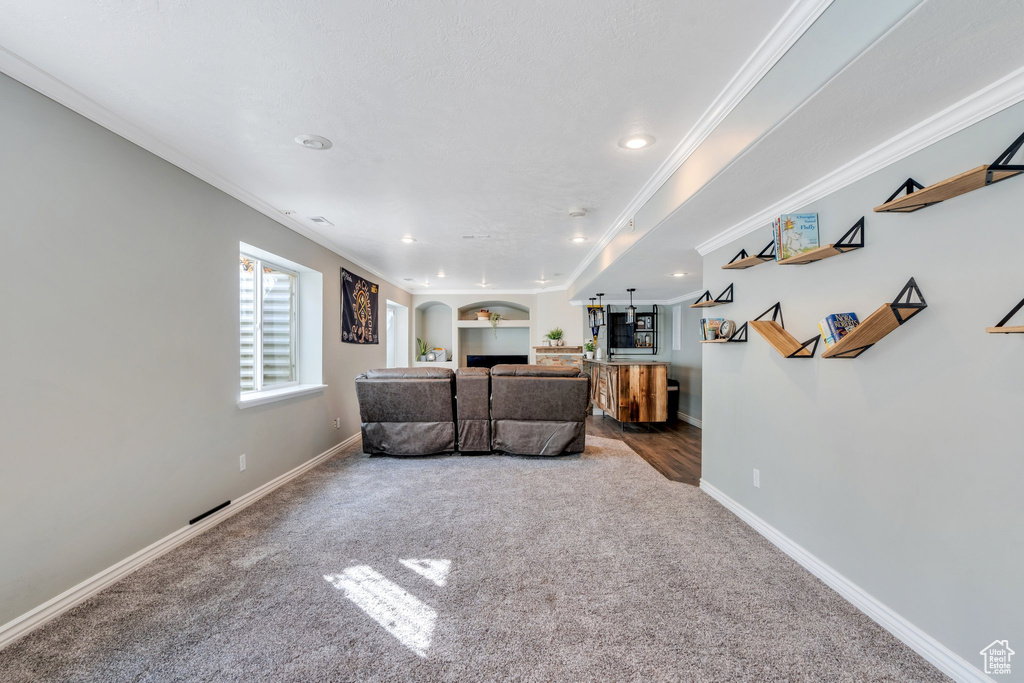 Carpeted living area featuring ornamental molding, arched walkways, baseboards, and recessed lighting