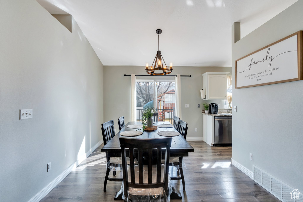 Dining area with a chandelier, dark wood-type flooring, visible vents, and baseboards