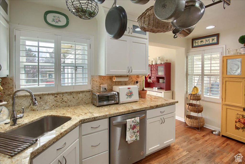 Kitchen with a sink, plenty of natural light, white cabinetry, and dishwasher