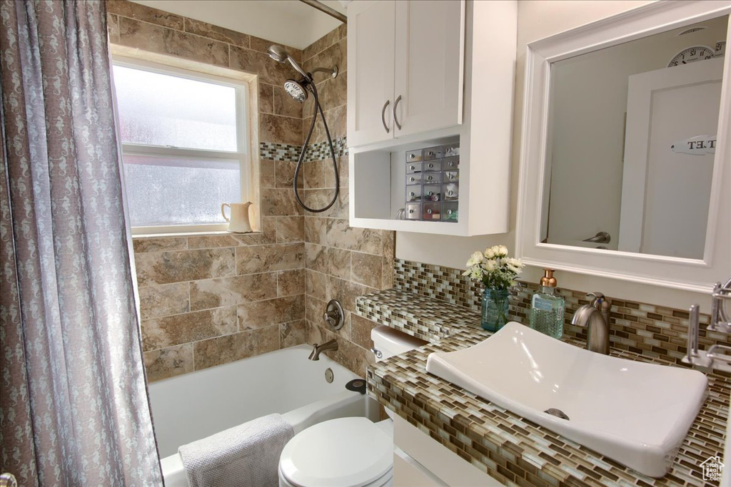 Bathroom with shower / tub combo, a sink, backsplash, and toilet