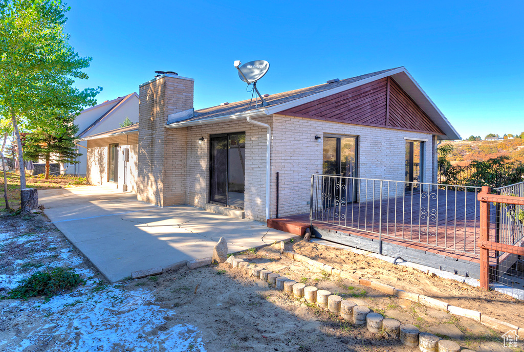 Mid-century home featuring brick siding, a chimney, fence, and a patio