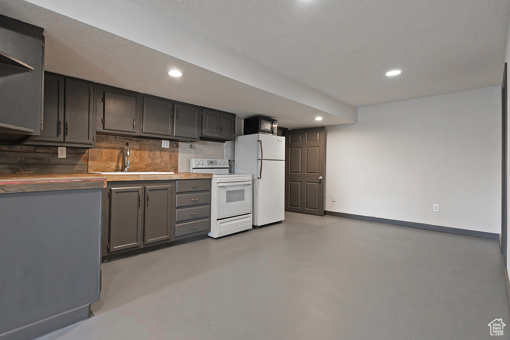 Kitchen featuring white appliances, baseboards, concrete flooring, and recessed lighting