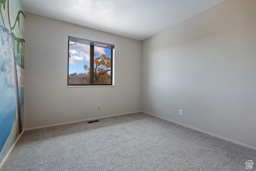 Carpeted empty room with baseboards and visible vents