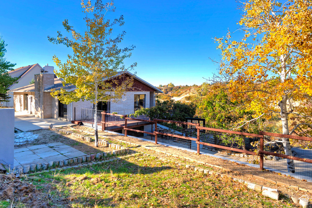 View of side of home with brick siding, fence, a chimney, and a patio