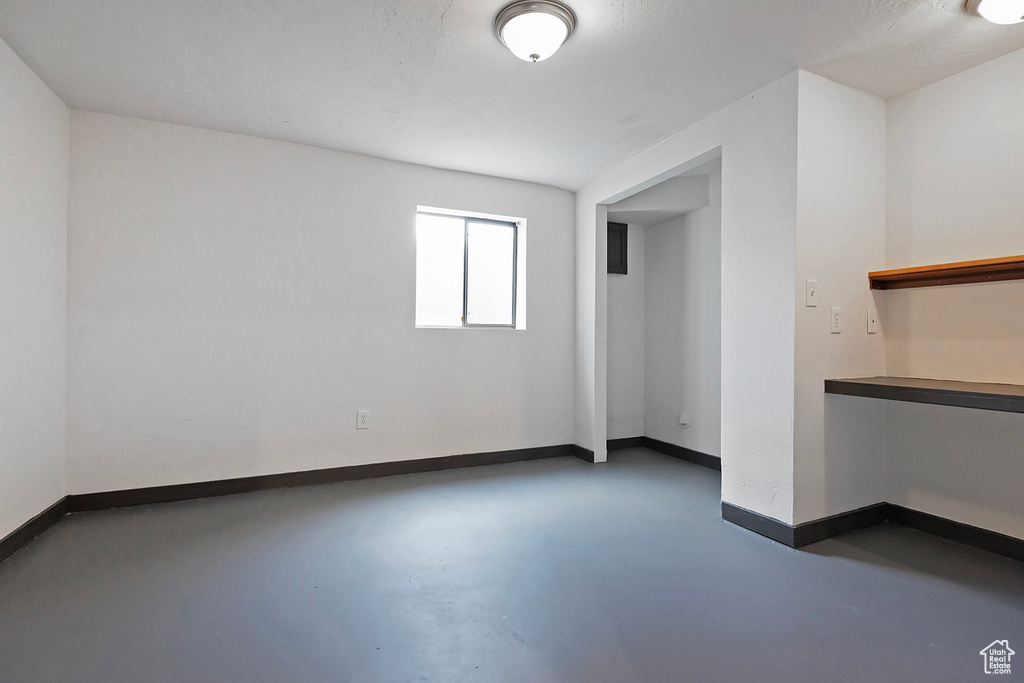 Empty room featuring finished concrete flooring and baseboards