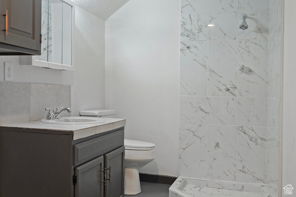 Full bathroom with toilet, baseboards, walk in shower, and vanity