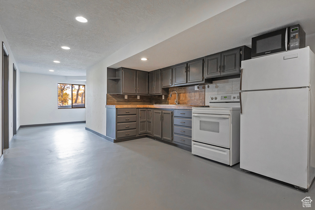 Kitchen featuring open shelves, tasteful backsplash, a sink, a textured ceiling, and white appliances