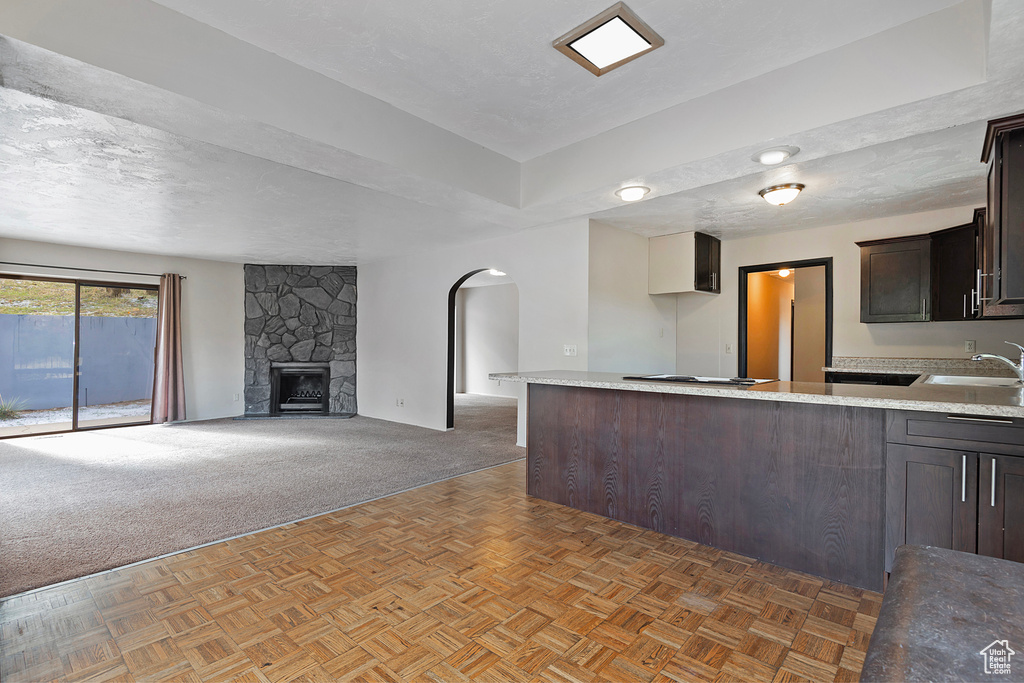 Kitchen with arched walkways, light countertops, a peninsula, and dark brown cabinets