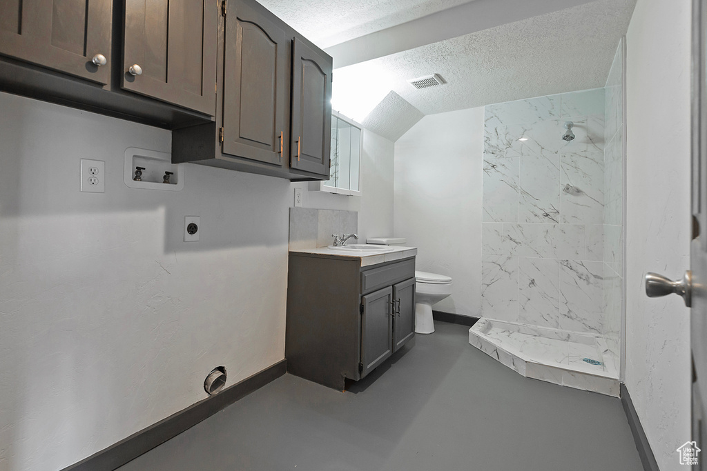 Clothes washing area featuring a textured ceiling, hookup for a washing machine, hookup for an electric dryer, a sink, and baseboards