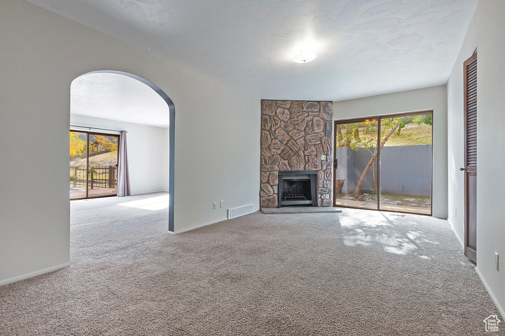 Unfurnished living room with carpet floors, a wealth of natural light, and visible vents