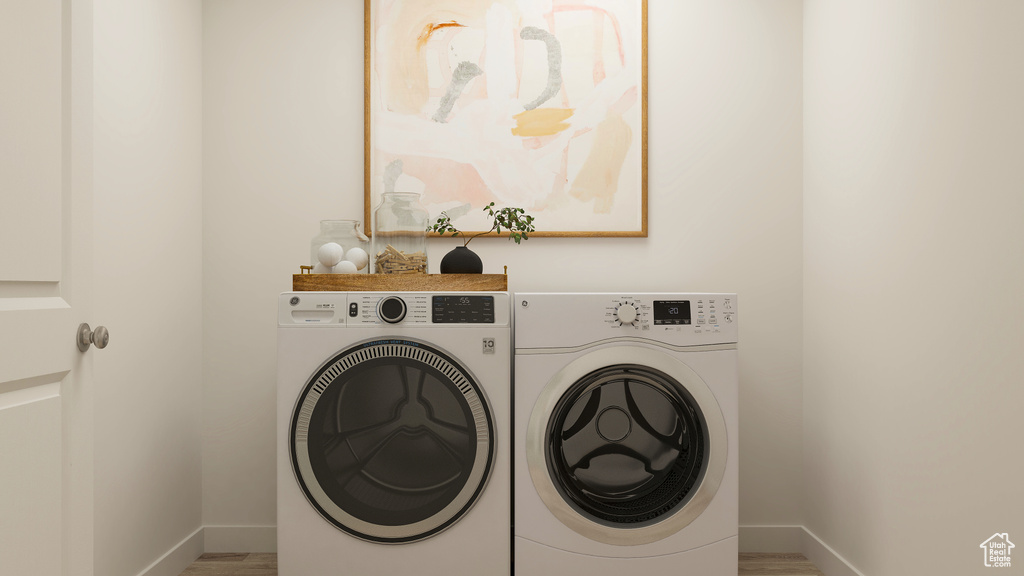 Washroom with laundry area, baseboards, separate washer and dryer, and wood finished floors