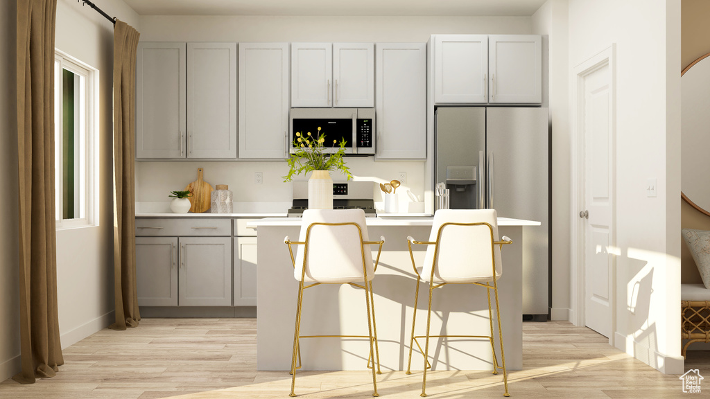 Kitchen with a breakfast bar, a kitchen island, stainless steel refrigerator with ice dispenser, gray cabinets, and light wood finished floors