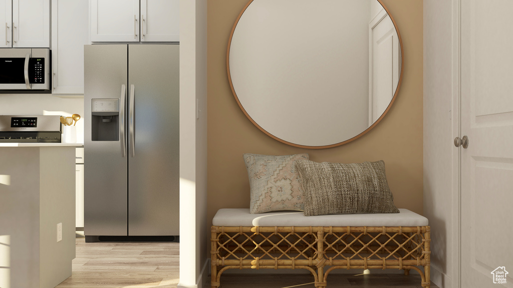 Interior space featuring range, white cabinetry, stainless steel refrigerator with ice dispenser, and light wood-style floors