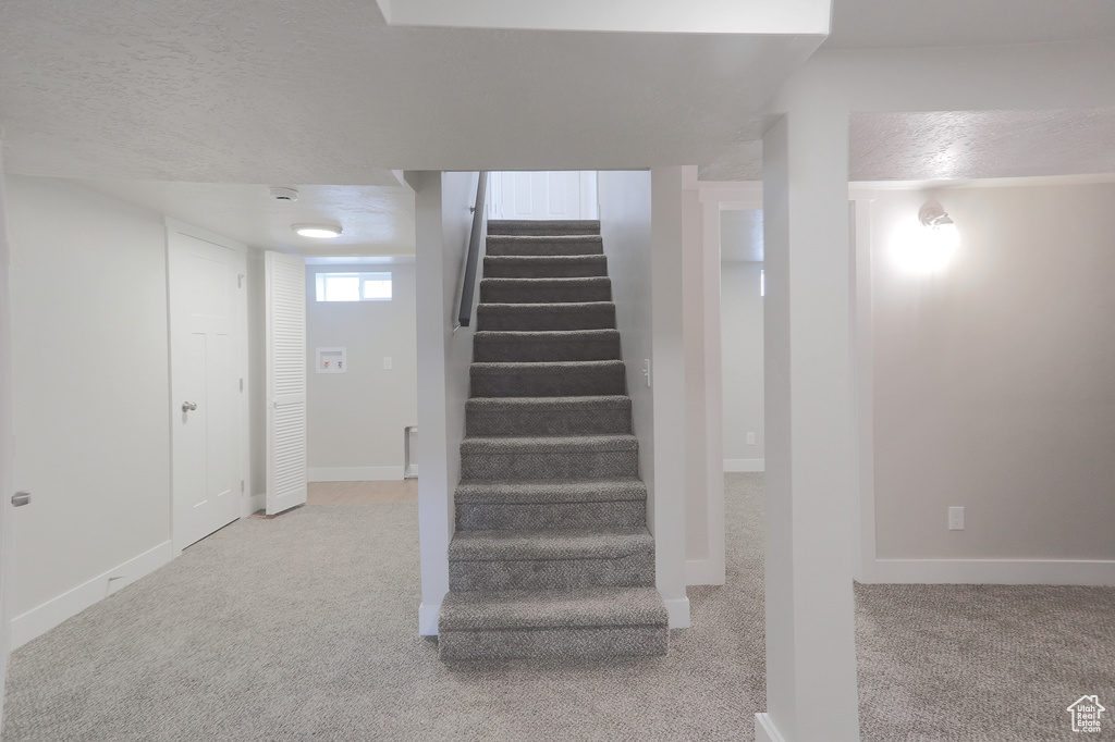 Staircase featuring carpet floors, baseboards, and a textured ceiling