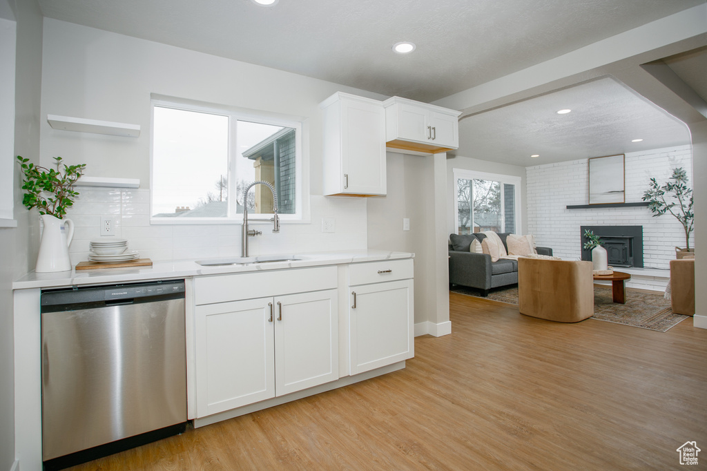 Kitchen featuring open shelves, light wood-style floors, white cabinets, a sink, and dishwasher