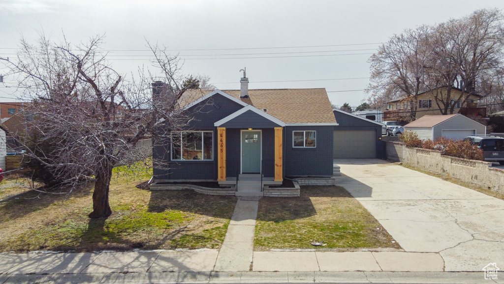 Bungalow-style home featuring driveway, a garage, a shingled roof, a chimney, and brick siding