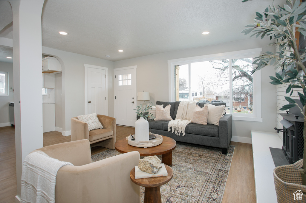 Living area with baseboards, arched walkways, wood finished floors, a fireplace, and recessed lighting