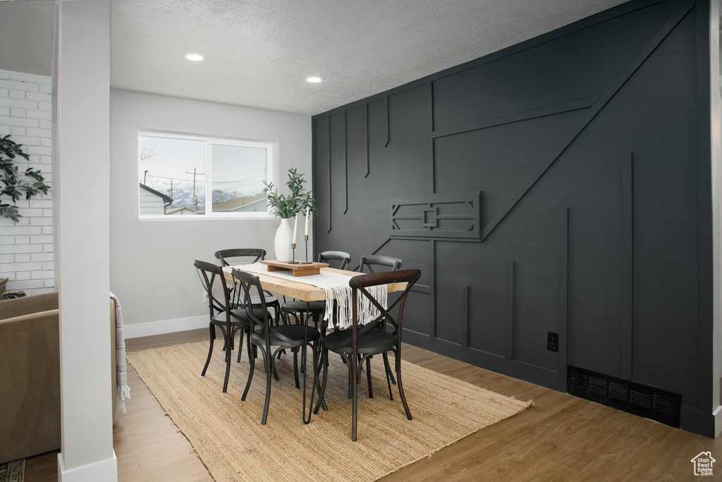 Dining area featuring recessed lighting, visible vents, a decorative wall, a textured ceiling, and light wood-type flooring