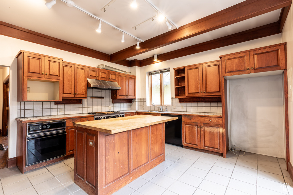 Kitchen featuring wood counters, a center island, under cabinet range hood, black appliances, and open shelves