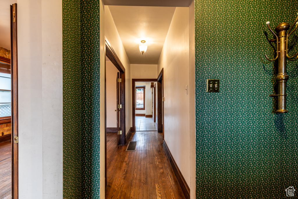 Corridor with wood finished floors, visible vents, and baseboards