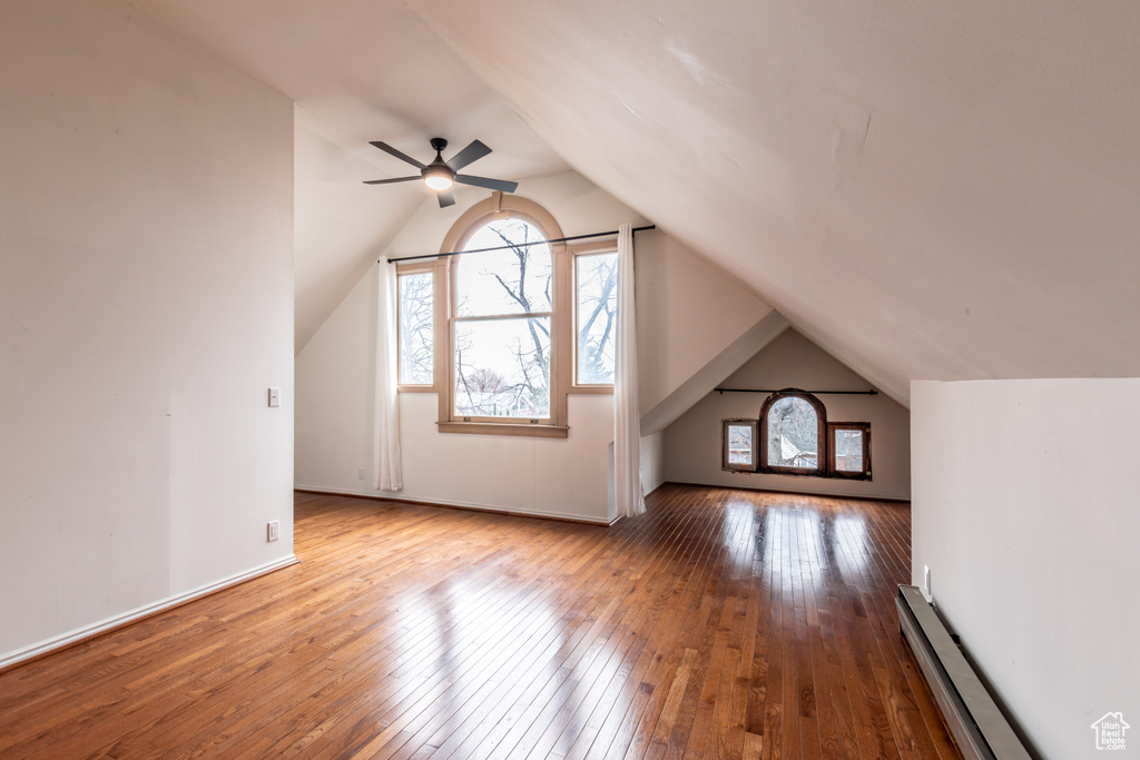 Additional living space with lofted ceiling, hardwood / wood-style flooring, and a baseboard radiator