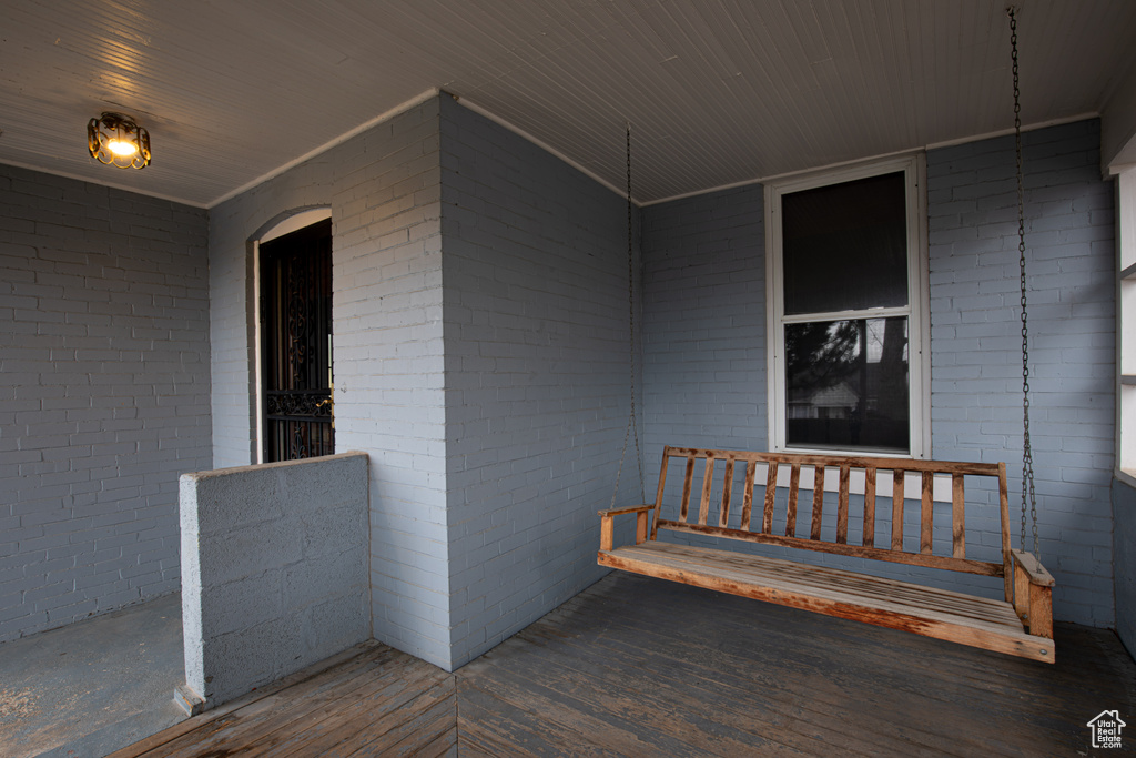 View of exterior entry featuring covered porch and brick siding