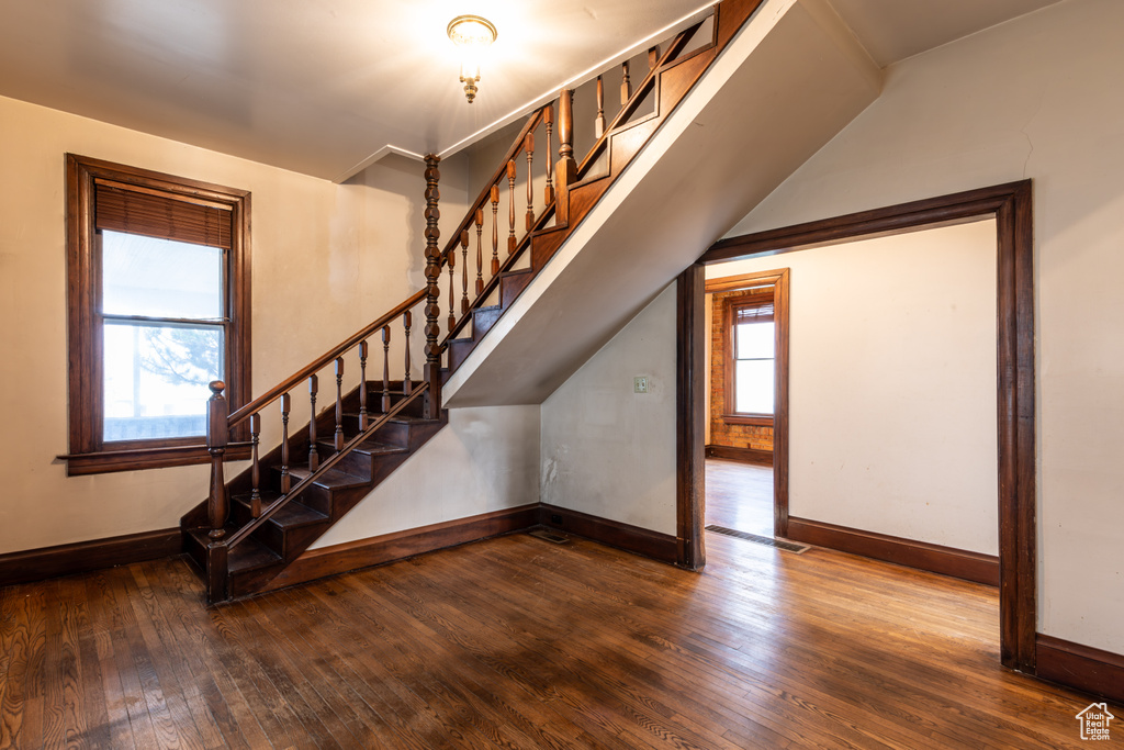 Staircase with plenty of natural light, visible vents, baseboards, and wood-type flooring