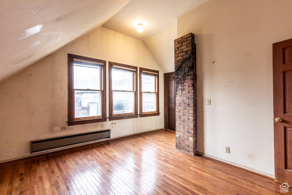 Additional living space featuring light wood-style floors, lofted ceiling, and baseboard heating