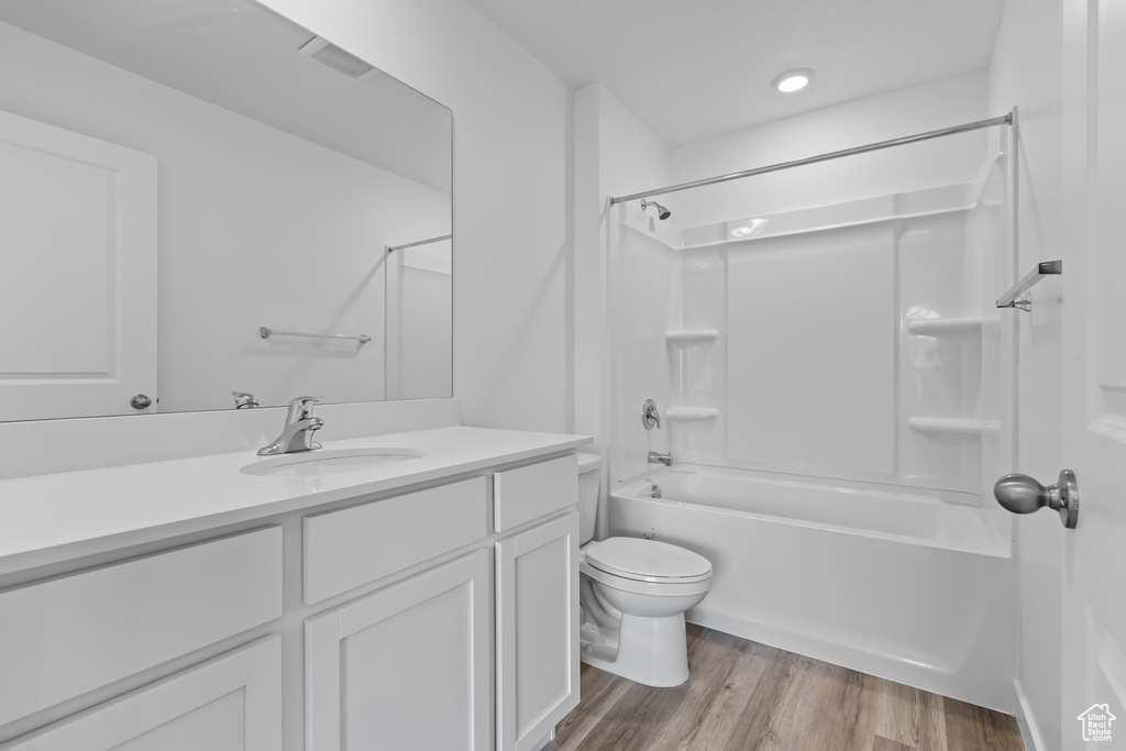 Full bathroom with vanity, shower / washtub combination, wood finished floors, and toilet
