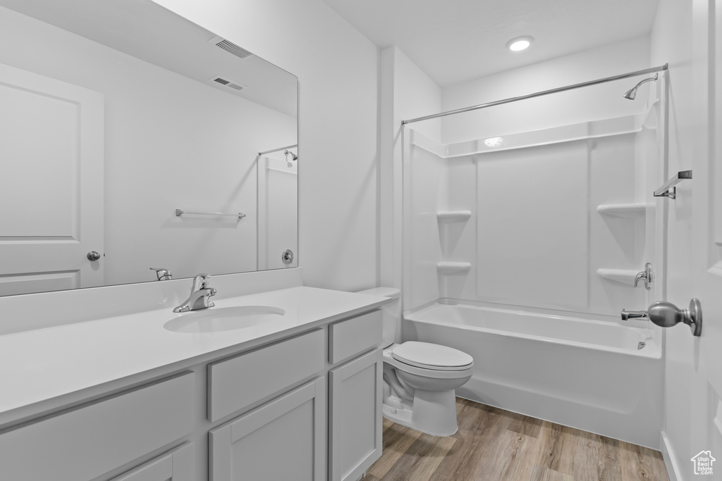 Bathroom with toilet, bathtub / shower combination, wood finished floors, and vanity