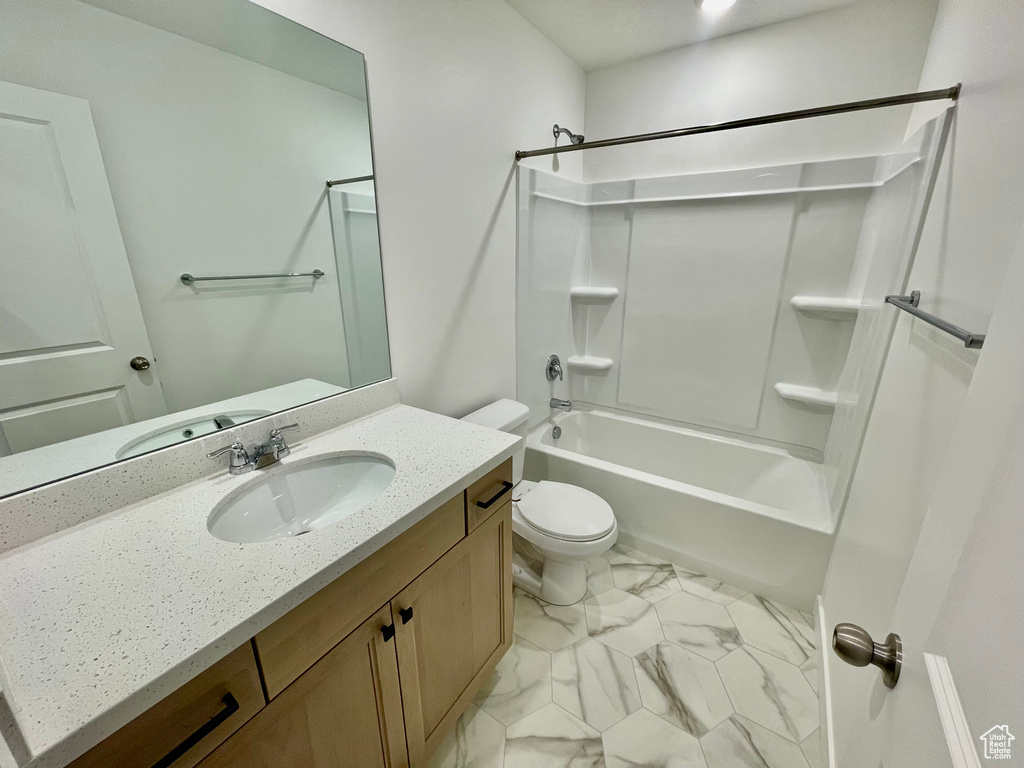 Bathroom with toilet, marble finish floor, tub / shower combination, and vanity