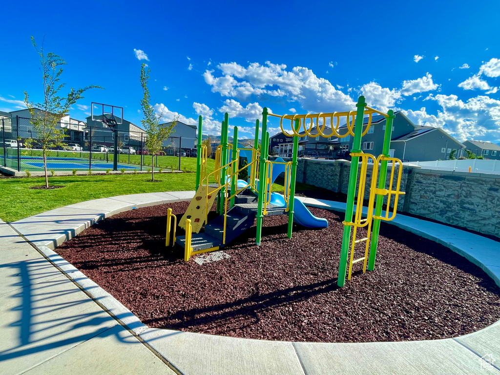 Community play area with a tennis court, a residential view, and fence