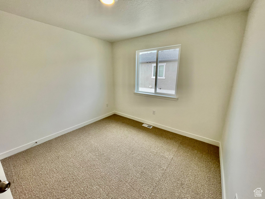 Unfurnished room featuring dark colored carpet, visible vents, and baseboards