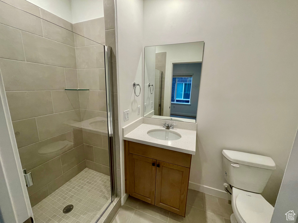 Bathroom with toilet, a shower stall, vanity, and tile patterned floors