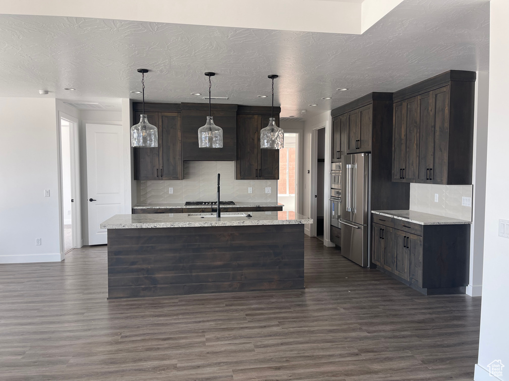 Kitchen featuring appliances with stainless steel finishes, dark brown cabinetry, backsplash, a textured ceiling, and recessed lighting
