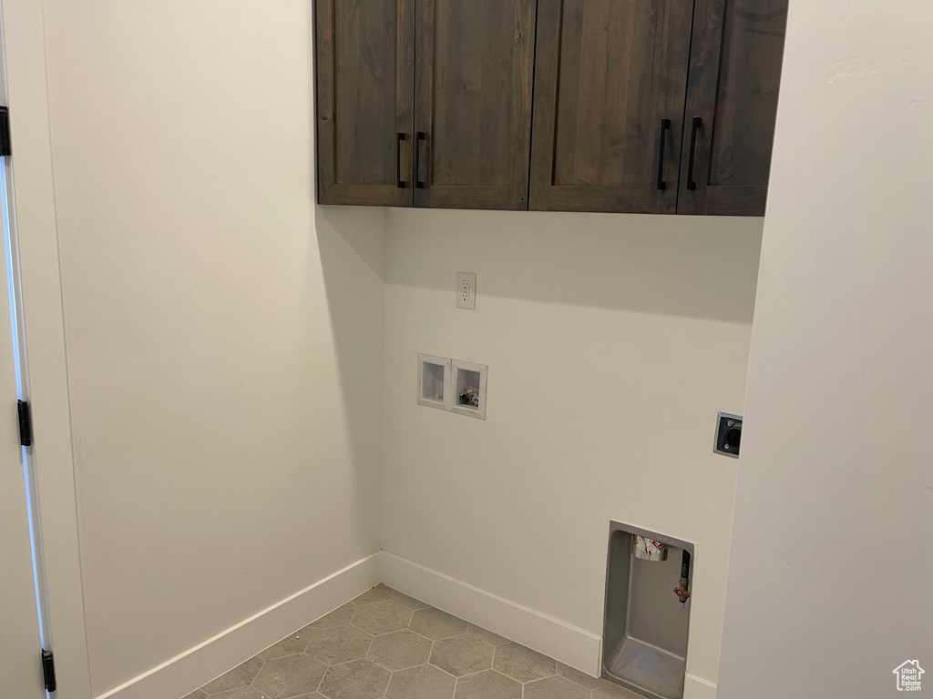 Washroom with cabinet space, electric dryer hookup, washer hookup, baseboards, and light tile patterned flooring