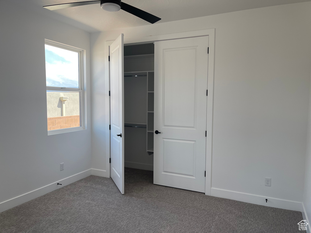 Unfurnished bedroom with carpet flooring, a closet, baseboards, and a ceiling fan
