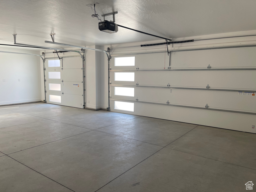 Garage featuring a garage door opener and baseboards