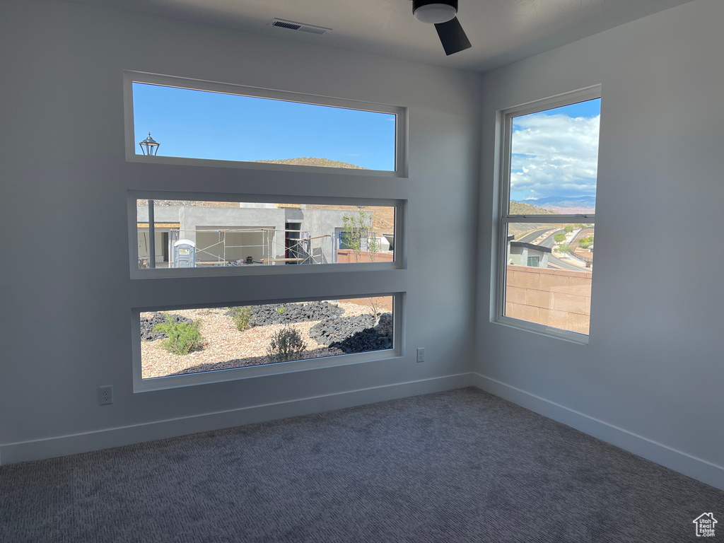 Carpeted empty room featuring a ceiling fan and baseboards