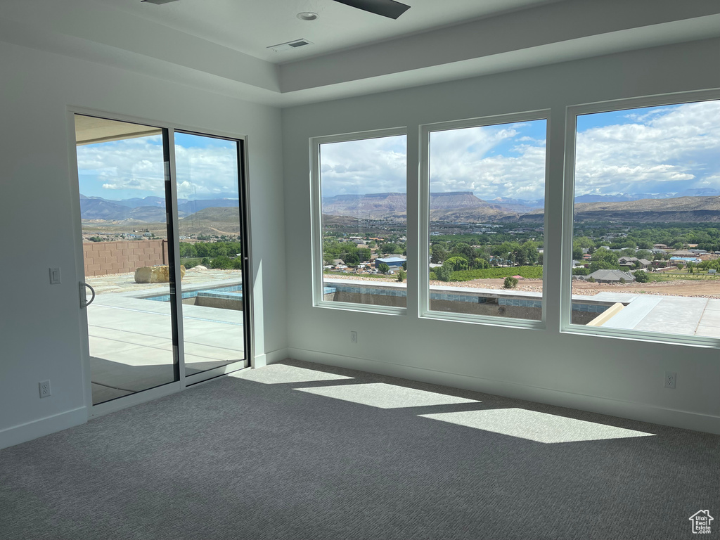 Empty room with a mountain view, carpet flooring, baseboards, and healthy amount of natural light