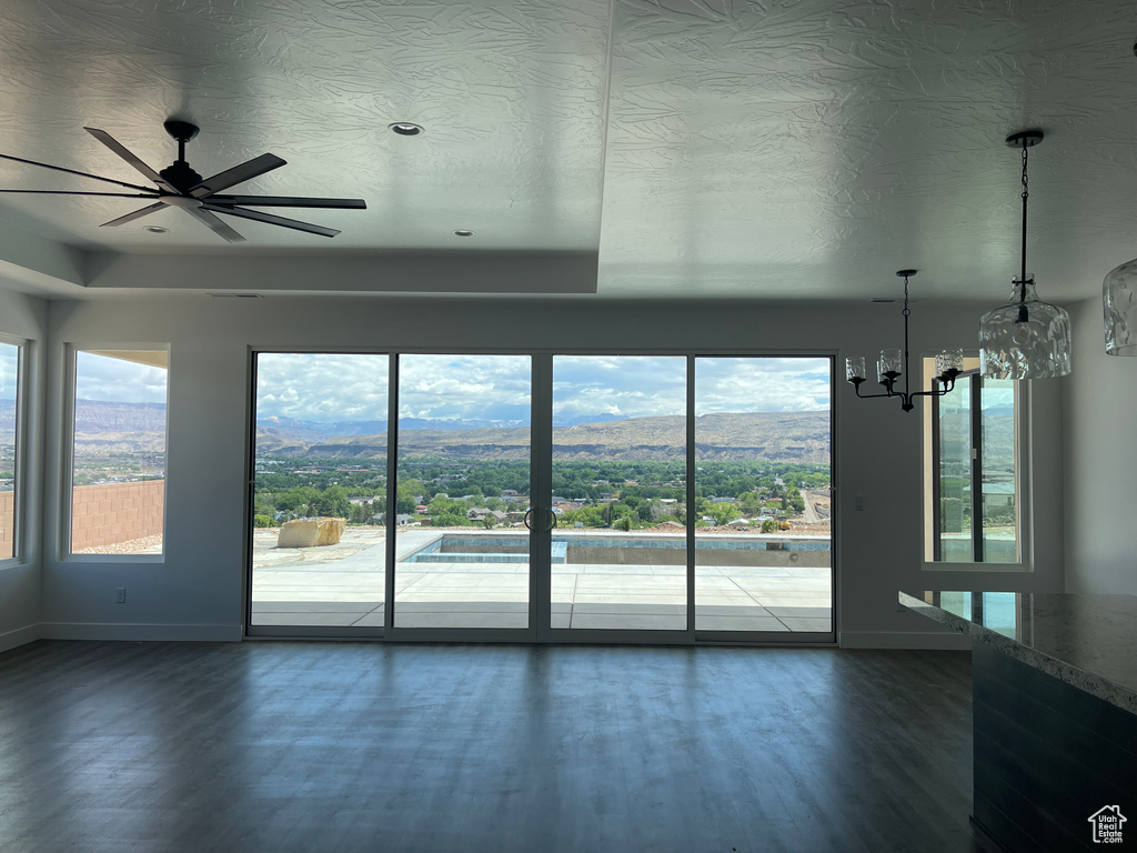 Empty room with baseboards, dark wood-type flooring, plenty of natural light, a chandelier, and a textured ceiling
