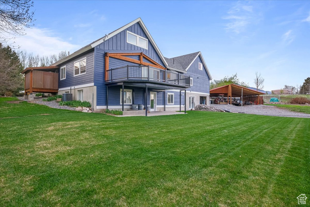 Rear view of property featuring a lawn, a wooden deck, central AC, and board and batten siding