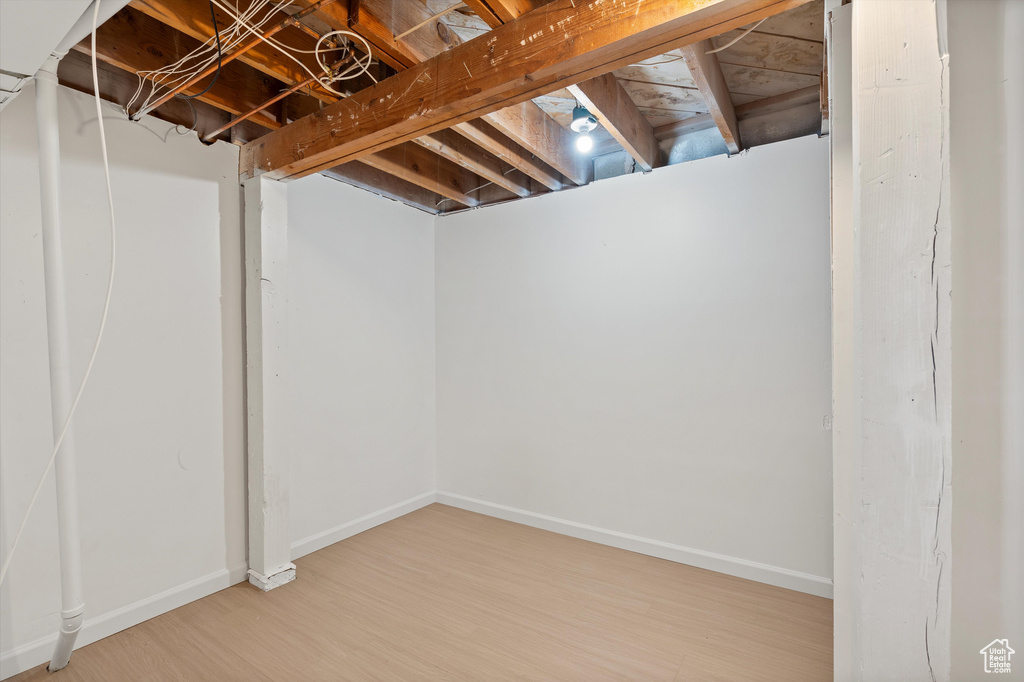 Unfinished below grade area featuring baseboards and wood finished floors