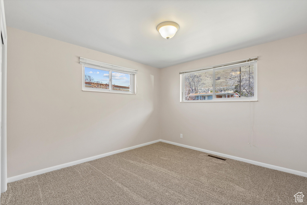 Carpeted empty room with visible vents and baseboards