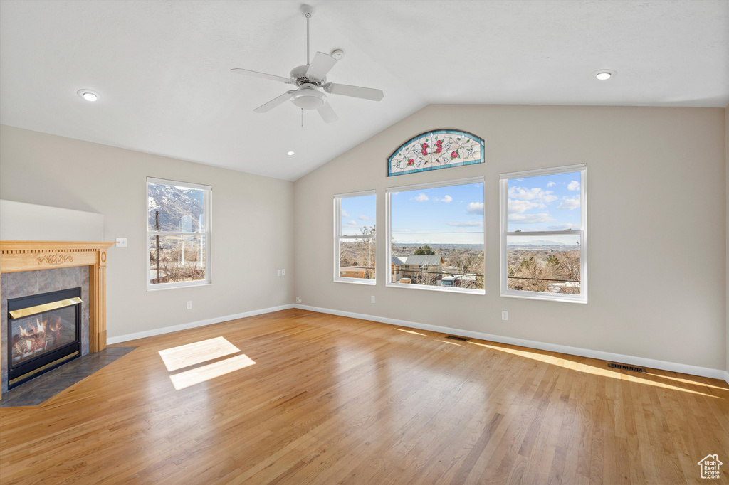 Unfurnished living room featuring a healthy amount of sunlight, light wood-type flooring, and a fireplace with flush hearth