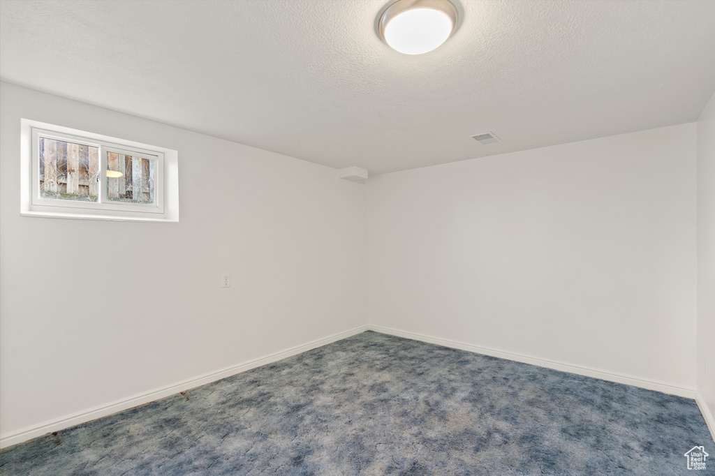 Spare room featuring a textured ceiling, baseboards, and carpet flooring