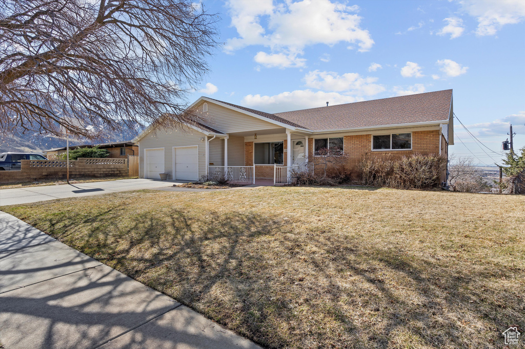 Single story home with a garage, brick siding, concrete driveway, covered porch, and a front yard