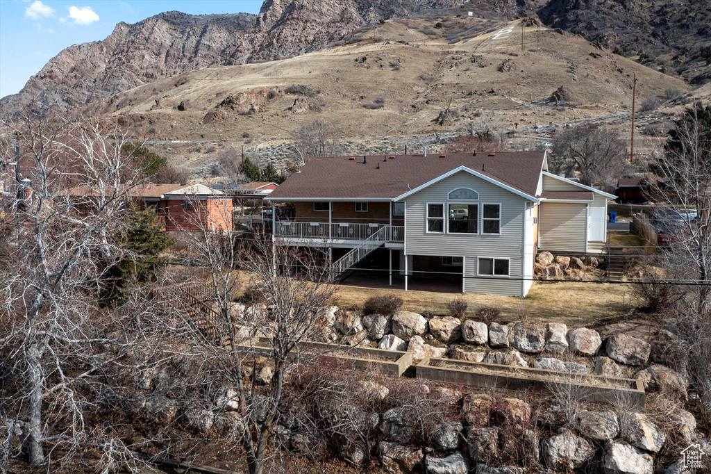 Rear view of property featuring a deck with mountain view and stairway